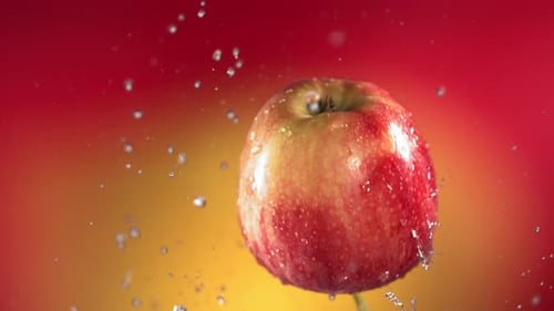 Fliegen von Red Apple auf rot-gelbem Hintergrund in Zeitlupe