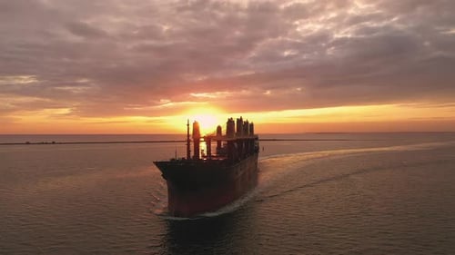 Slowmotion Cargo Bulker Ship Bulk Carrier with Deck Cranes Sailing in Sunset Front View Merchant