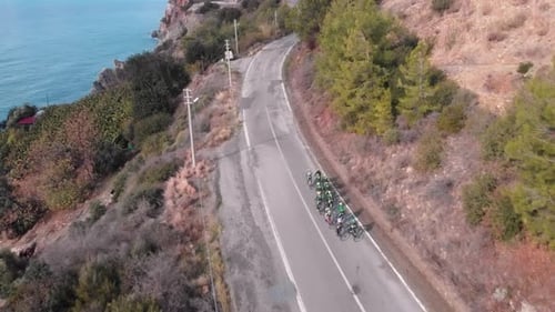 Ciclistas en bicicleta por carretera de montaña a lo largo de la costa