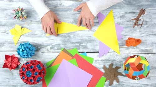 Mann faltet Origami am Arbeitsplatz.