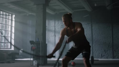 Man Training with Battle Ropes in Gym