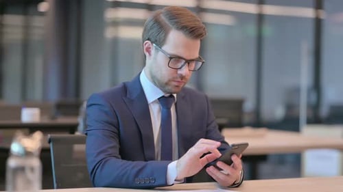 Businessman Browsing Internet on Smartphone in Office
