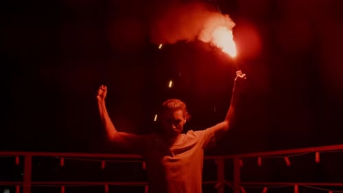 Figure Holding Red Smoke Flare at Night