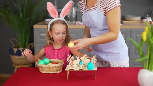 Frau und kleines Mädchen dekorieren Ostertisch