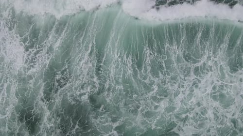 Top down aerial view of giant ocean waves crashing and foaming