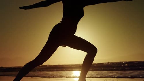 Silhouette of woman doing yoga on the beach