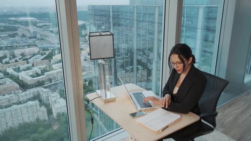 Young Business Woman Working on a Laptop in a Modern Office Located on the High Floor of a