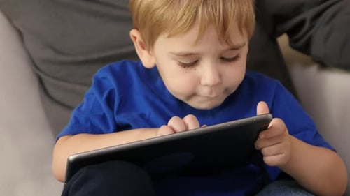 Child Using Tablet with Adult Nearby Indoors