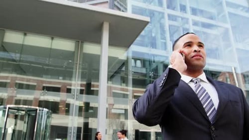 Businessman Talking on Phone Outside Glass Building