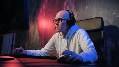 Young Man Puts On Headphones at Computer Desk