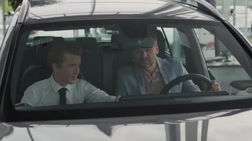 Salesman and Customer Sitting in Car in Dealership