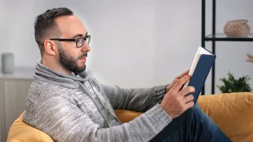 Man with Glasses Reading a Book on Couch