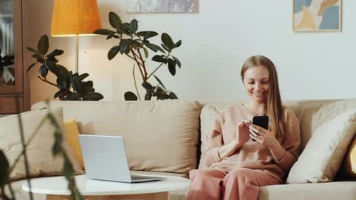 Smiling Woman Using Smartphone in Home Living Room