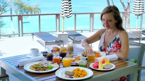 Happy Woman Eat Breakfast or Brunch in Luxury Outdoors Restaurant at Tropical Hotel in Sunny Summer