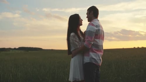 Couple Embraces in Field at Sunset