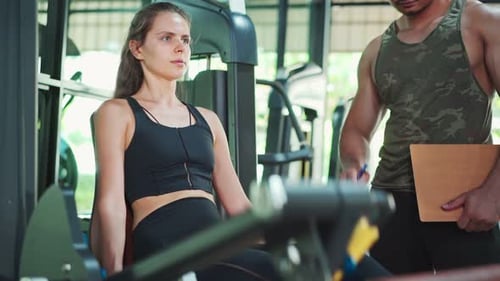 Asian Fitness trainer teach young sportswoman doing leg press exercise for muscle at gym stadium.
