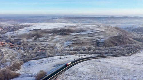 Aerial View of a Winding Road With Driving Trucks in a Frosty Winter Sunny Day