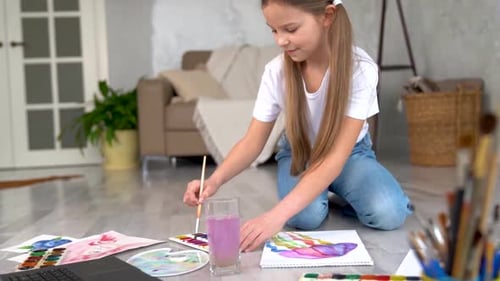 Girl Painting with Watercolors on Floor at Home