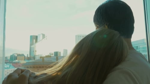 Young Couple Enjoying City View Through The Window