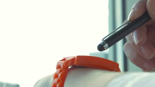 Stylus Interacts with Orange Smartwatch Device on Wrist