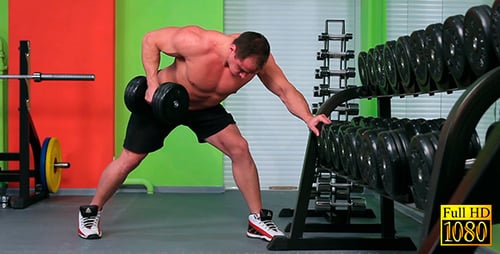 Shirtless Man Working Out With Dumbbell in Gym