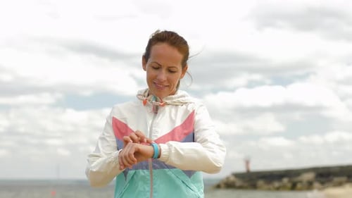 Woman with Fitness Tracker Running Along Beach