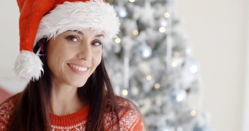 Smiling Woman in Santa Hat by Christmas Tree