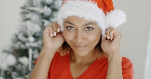 Smiling Woman in Santa Hat Near Christmas Tree