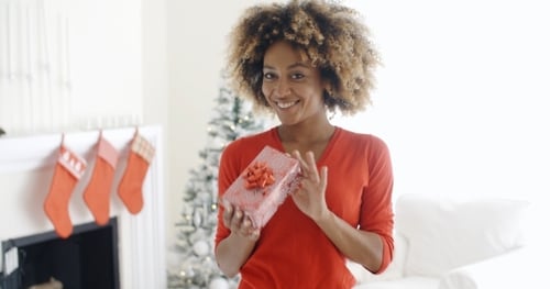 Smiling Woman Holds Christmas Gift in Home