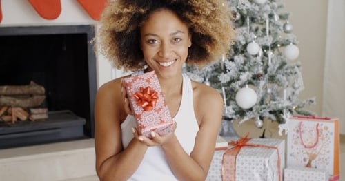 Smiling Woman Presents a Christmas Gift Indoors