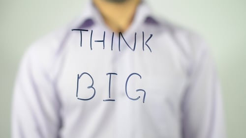 Person Writes "Think Big" on Glass Surface