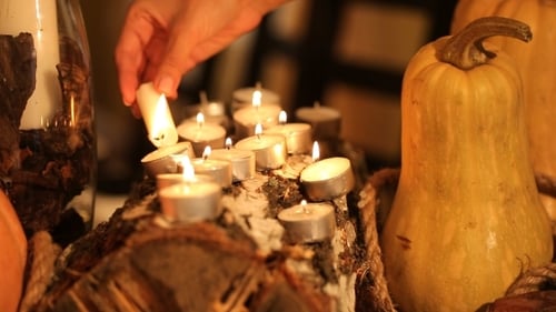 Hand Lighting Candles among Pumpkins