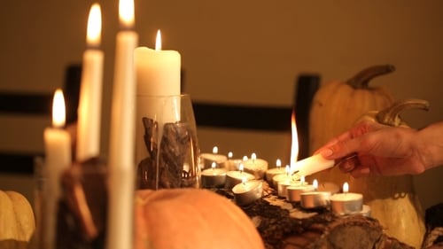 Hand Lighting Candles Among Pumpkins for Festivities