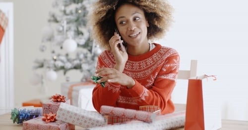 Woman Chatting On a Mobile As She Wraps Gifts