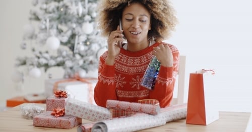 Woman Chatting On a Mobile As She Wraps Gifts