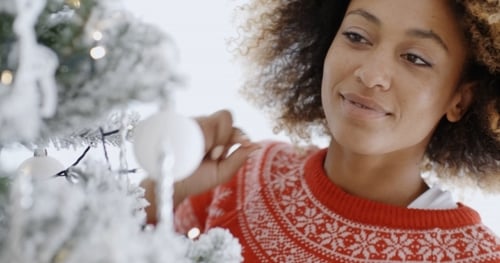 Woman Decorating Christmas Tree with White Ornaments