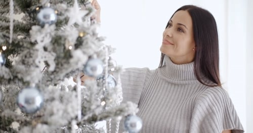 Woman Decorating Christmas Tree with Silver Ornaments