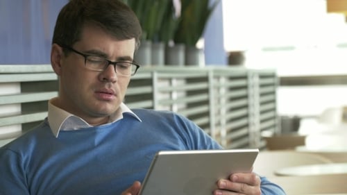 Young Businessman Working On Tablet PC In Cafe