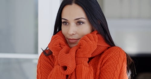 Woman In Orange Sweater and Gloves Keeping Warm Indoors