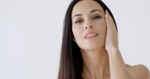 Woman Gently Touching Her Face and Smiling