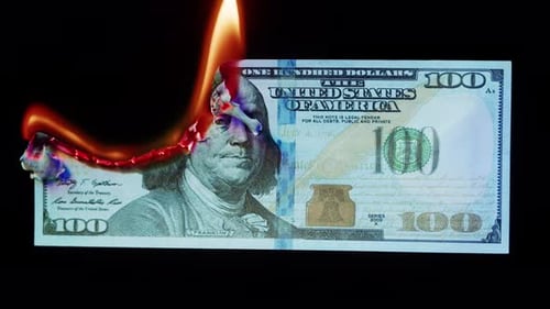 Brennende amerikanische Hundert-Dollar-Banknote auf schwarzem Hintergrund