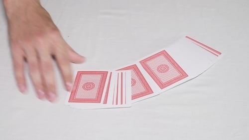 Hand Playing with Cards on White Surface