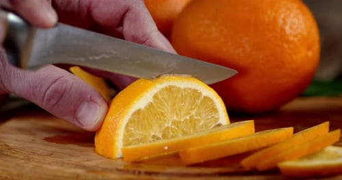 Male Hand with Knife Is Ground Fresh Orange on Cutting Board.