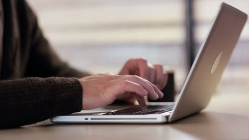 Hands Typing on Silver Laptop at Desk