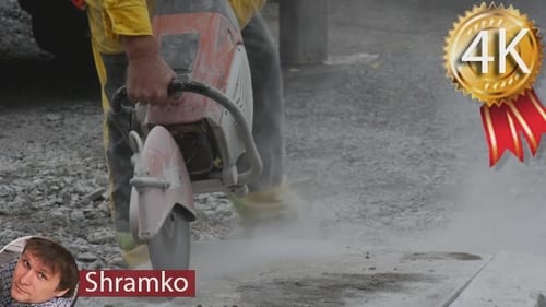 Man Worker in Yellow Workwear is Grinding The
