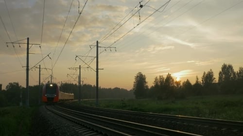 Personenzug in ländlicher Gegend bei Sonnenuntergang