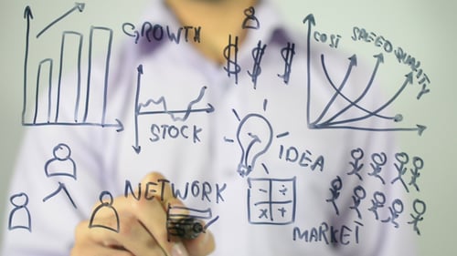 Man Drawing Business Diagrams on Glass Surface