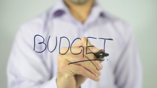 Hand Writes Budget on Clear Surface