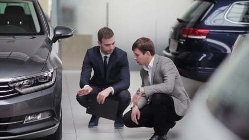 Men Discuss Car Details in Dealership Showroom