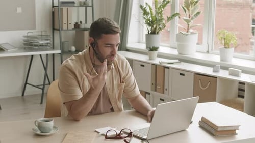 Man in Headset at Laptop During Video Call